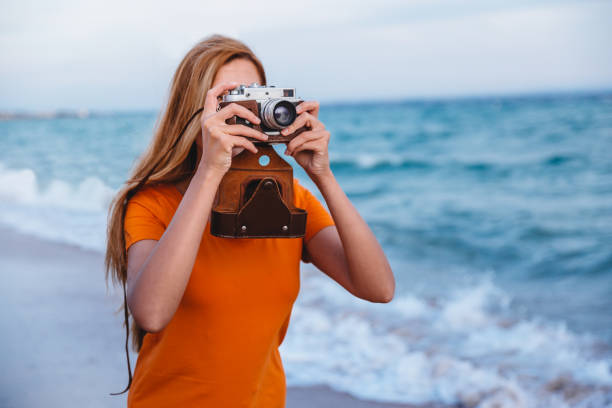 istock Woman with retro camera on the beach 1224212114