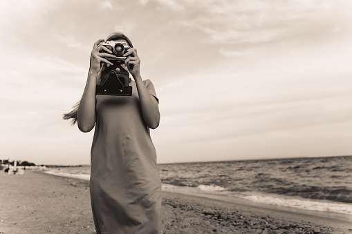 Caucasian woman with retro camera on the sandy beach