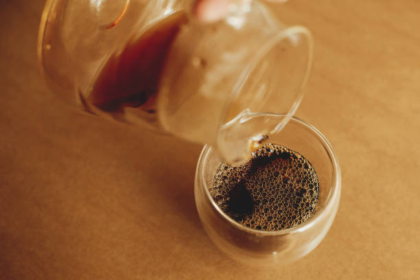 istock Brewing alternative coffee, v60. Pouring fresh aromatic coffee from glass kettle in cup on brown background. Barista making filter coffee 1224213937