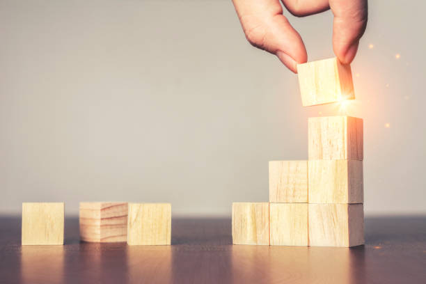 istock Hand arranging wood block stacking as step stair on table.New normal Business 1224217484