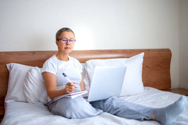 istock Mature woman working from home on the bed 1224218893