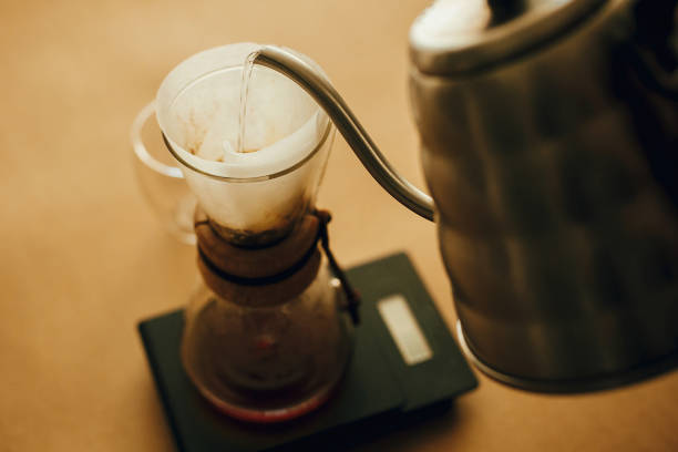 istock Alternative coffee brewing v60. Barista making filter coffee on brown background. Pouring hot water from steel kettle in filter with ground coffee in pour over on scale. 1224219206