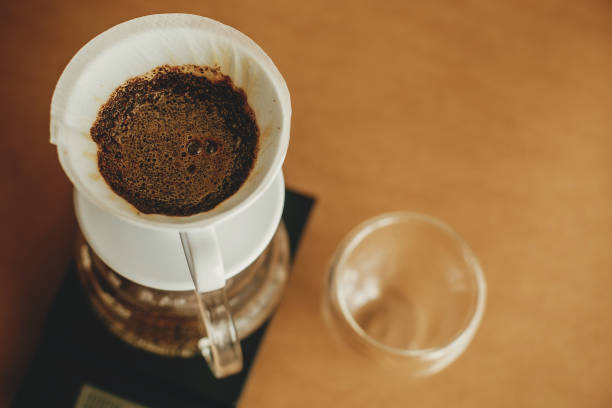 istock Drip coffee. Brewing aromatic fresh coffee in paper filter closeup in pour over on scale. Alternative coffee brewing v60 closeup. Barista making filter coffee on brown background 1224219309