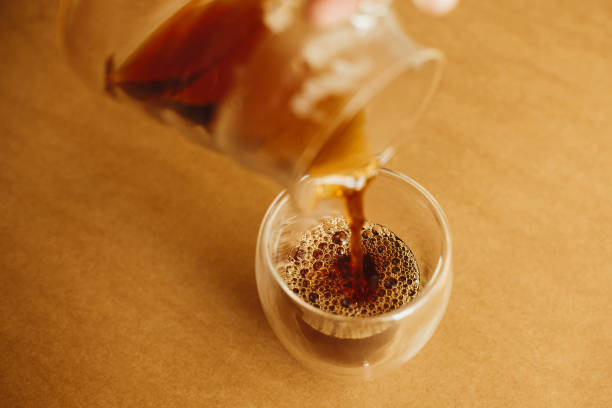 istock Pouring fresh aromatic coffee from glass kettle in cup on brown background. Brewing alternative coffee, v60. Barista making filter coffee 1224220655