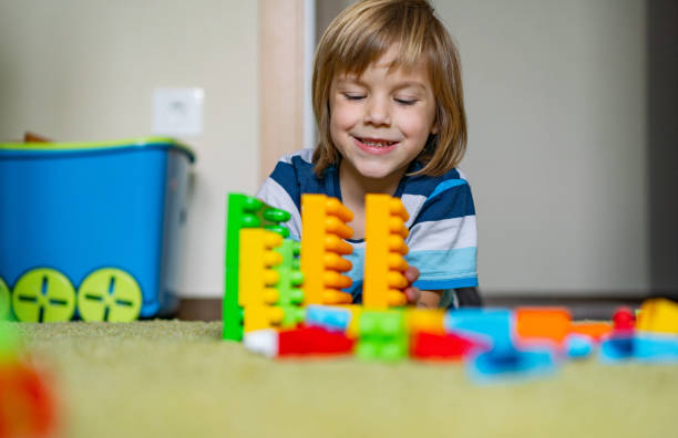 istock Cute boy lying on the floor and plays with colorful plastic blocks 1224222338
