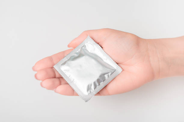 mão das mulheres e preservativo sobre um fundo branco, dar preservativo, conceito de sexo seguro - sexual issues aids condom human pregnancy - fotografias e filmes do acervo