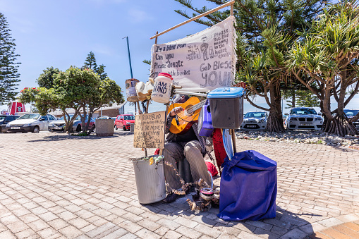 Blind man and beggar with his one man band creation at the beach road in Port Elizabeth, South Africa