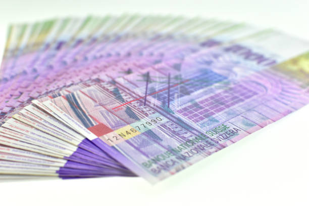Three piles of different currencies on the table - dollars, swiss and euros.