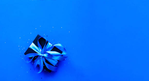 istock Black gift box on a blue background with sparkles. Fathers Day concept. Close-up 1224226440