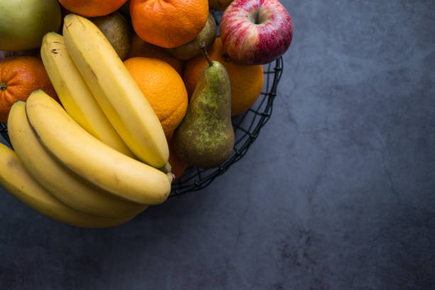 manzanas, plátanos, peras, mandarinas y naranjas sobre un tazón de frutas sobre fondo de hormigón. comida saludable. vista superior. copiar espacio. - tazón para frutas fotografías e imágenes de stock