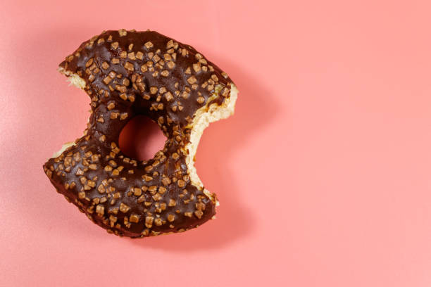 istock Bitten tasty chocolate donut on a pink background. Top view 1224229799