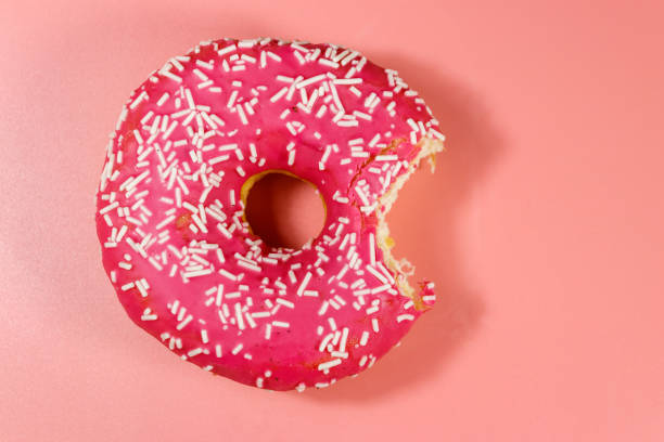 istock Bitten tasty pink donut on pink background. Top view 1224229801
