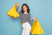 Conceptual photo of happy girl holds shopping packages on blue background