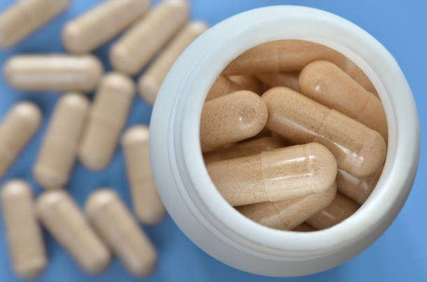 istock Medicinal bottle with pills on a light blue defocused background with scattered capsules 1224239524