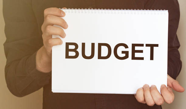 istock Man holding brochure with BUDGET text on grey background. Mock up for design 1224239989