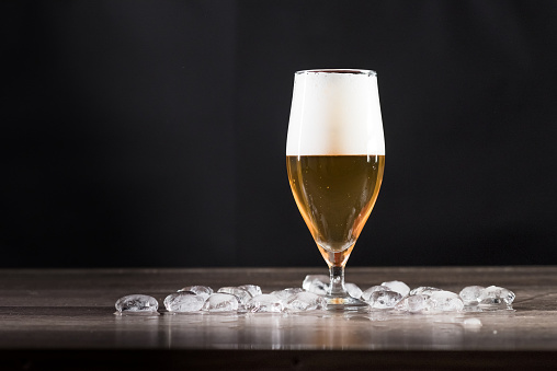 A glass of light beer is on the table with ice. The concept of relaxation, bars and parties.