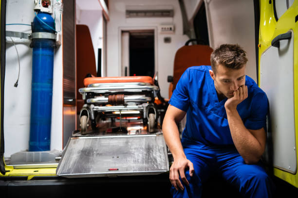A pensive paramedic sitting on the edge of an ambulance car stock photo