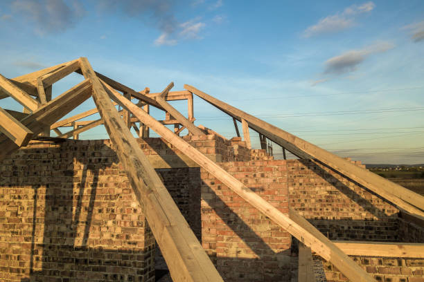 istock Private residential house with wooden roof frame structure under construction. Unfinished brick building under development. 1224248033