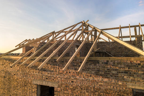 istock Private residential house with wooden roof frame structure under construction. Unfinished brick building under development. 1224248034
