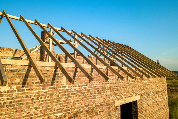istock Unfinished brick house with wooden roof structure under construction. 1224248106