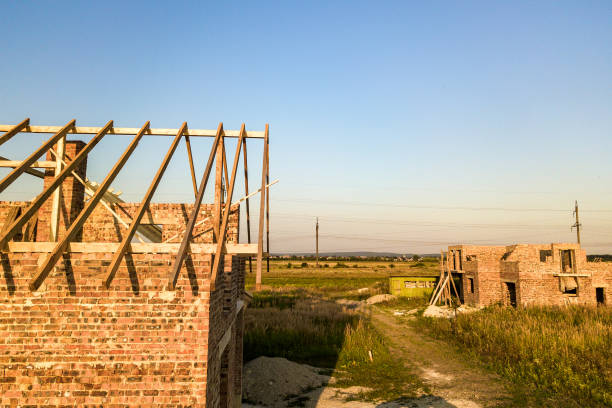 istock Unfinished brick house with wooden roof structure under construction. 1224248110