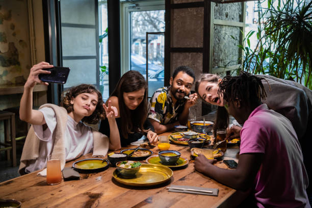istock Five young friends sitting at the table in a cafe, taking selfie 1224248267