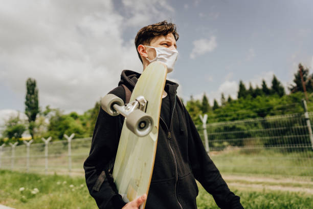 istock Skateboarder walking down the street with a mask on his face 1224252377