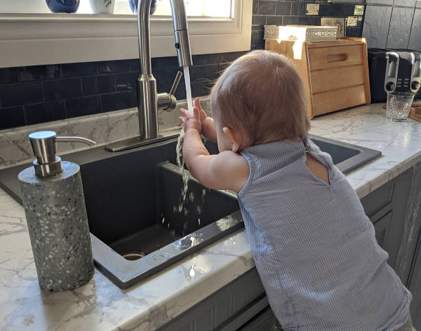 istock 17 Month Old Toddler Learning to Wash her Hands in the Kitchen Sink (During the Covid 19 Virus Pandemic) 1224253565
