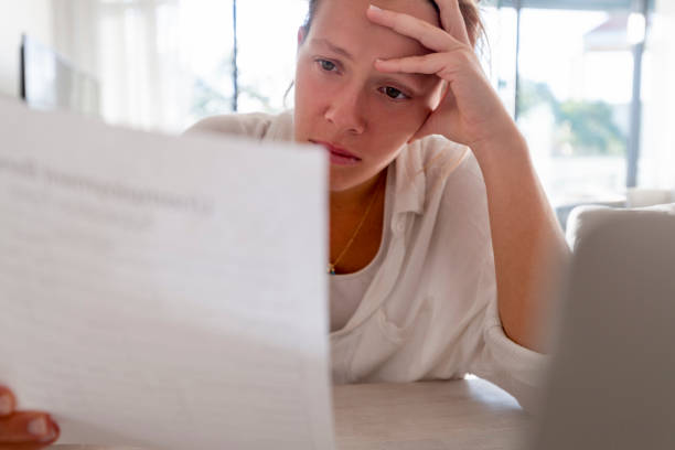 istock Woman looking worried holding paperwork at home. 1224254310