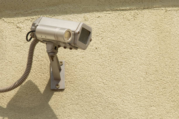 An old and dirty security camera mounted on a brick wall.