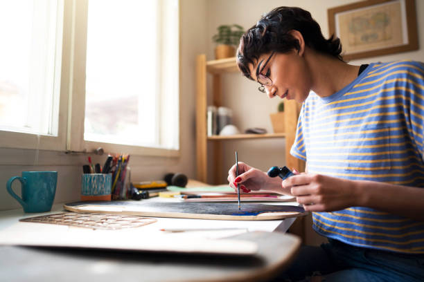 istock Young woman paints details  as a final touch on a new skateboard 1224255204