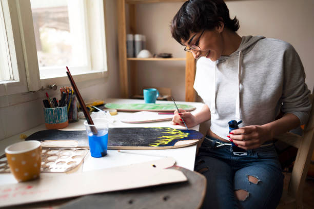 Young female artist is painting on a skateboard plank