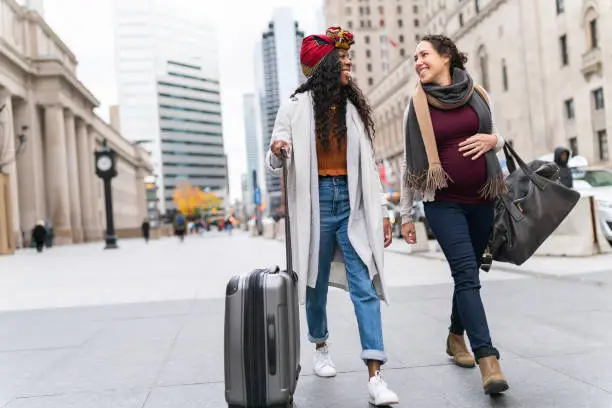 Photo of Pregnant woman with female friend exploring city while on vacation