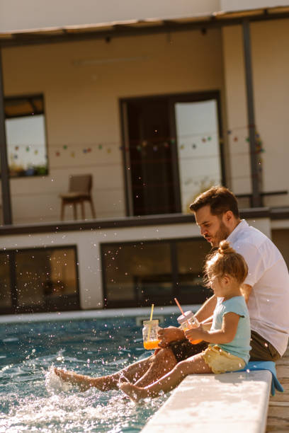 istock Father teaching daughter to splash water by the pool 1224263189