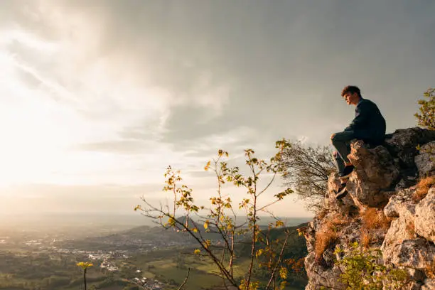 Photo of Teenager Sitting on the Edge of a Rock Cliff