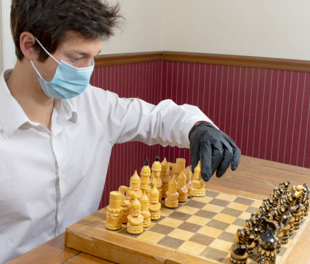 istock Young man playing chess wearing protective mask and gloves 1224266335
