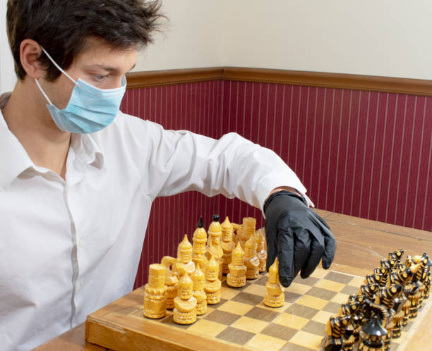 istock Young man playing chess wearing protective mask and gloves 1224266343