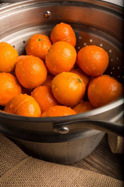 istock Fresh washed juicy small oranges in a colander on the table lying surrounded by burlap on wooden brown background. A good source of vitamin C and fiber. Boost immune system 1224267015