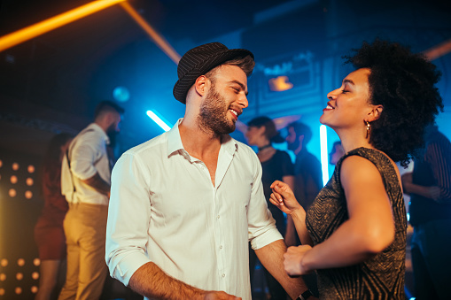 An affectionate young couple dancing on a crowded dance floor in a nightclub