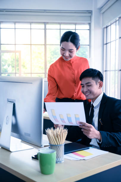 istock Business couple working together with graph paper and computer information at office workplace. 1224269691