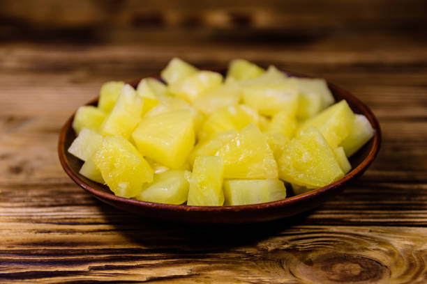 Ceramic plate with chopped canned pineapple on wooden table stock photo