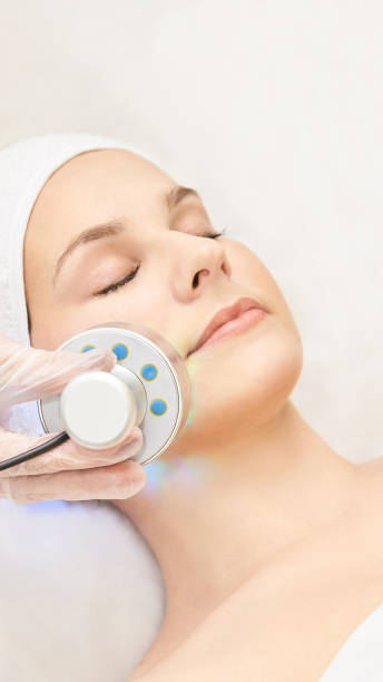 terapia infravermelha leve. procedimento de cabeça de cosmetologia. cara de mulher bonita. dispositivo de salão de cosméticos. rejuvenescimento da pele facial - galvanic - fotografias e filmes do acervo