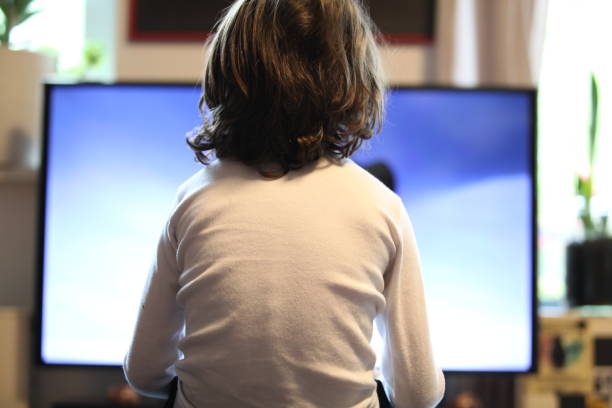 arrière de l’enfant de 6 ans à la maison regardant la tv - solitary confinement photos et images de collection