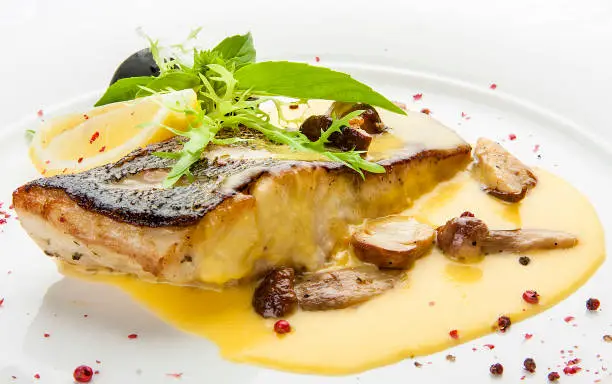 Pike perch with porcini mushrooms and potatoes. On a white plate