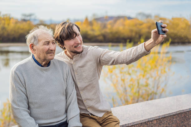 um homem tira uma selfie com um homem mais velho - 11873 - fotografias e filmes do acervo