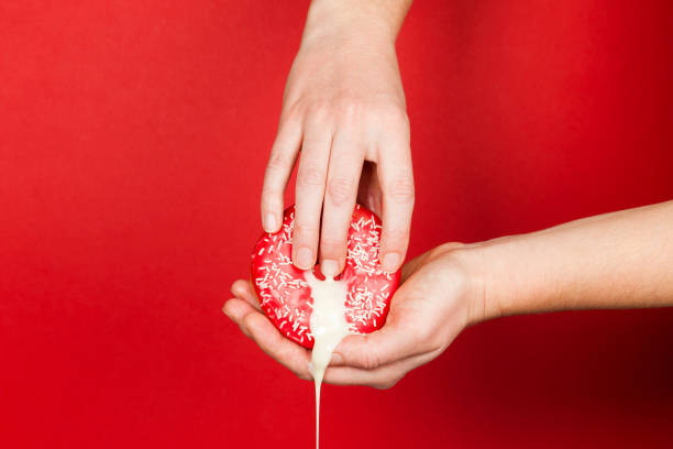 female hands and a donut on a red background as a symbol of masturbation and foreplay (prelude) before sex. touch the clitoris, erotic concept - homosexual beautiful sensuality love imagens e fotografias de stock