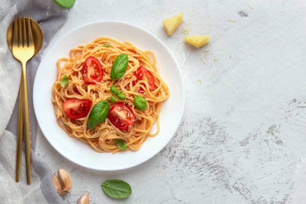 istock Pasta with cherry tomatoes, cheese and basil on a light background 1224300565