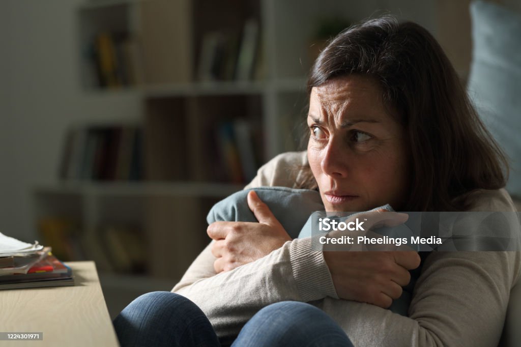 Scared middle age woman looking away at night at home Scared middle age woman looking away sitting on the floor holding pillow at night at home Fear Stock Photo