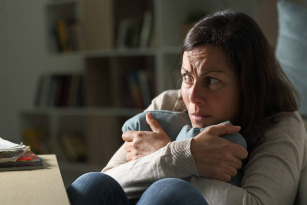 Scared middle age woman looking away at night at home Scared middle age woman looking away sitting on the floor holding pillow at night at home terrified stock pictures, royalty-free photos & images