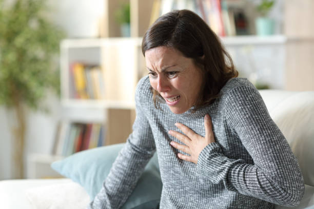 Adult woman suffering heart attack at home stock photo